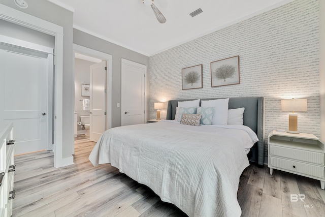 bedroom with wallpapered walls, baseboards, visible vents, light wood-style flooring, and an accent wall