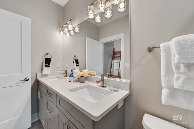 bathroom featuring double vanity, a sink, and toilet