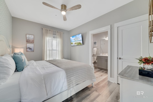 bedroom with ensuite bathroom, ceiling fan, light wood finished floors, and baseboards