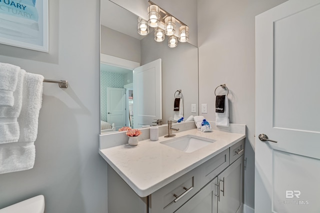 half bathroom with a chandelier, vanity, and toilet