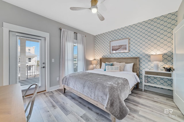 bedroom featuring light wood-style flooring, an accent wall, access to exterior, baseboards, and wallpapered walls