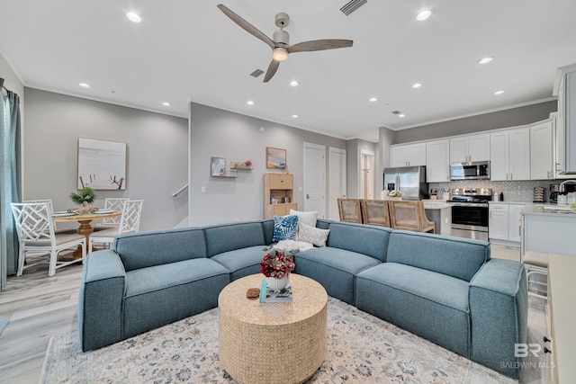 living area with recessed lighting, visible vents, ornamental molding, light wood-style floors, and ceiling fan