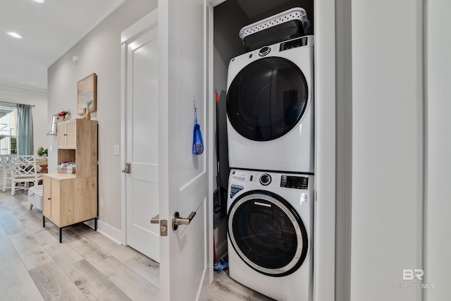 clothes washing area featuring light wood-type flooring, stacked washer / drying machine, and laundry area