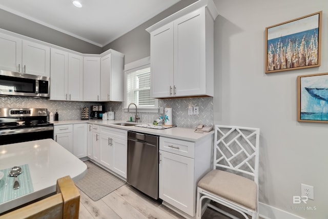 kitchen with white cabinets, decorative backsplash, appliances with stainless steel finishes, light countertops, and a sink