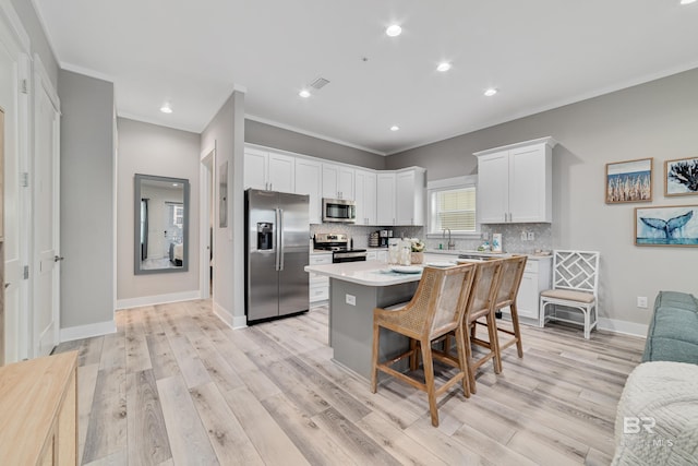 kitchen with crown molding, stainless steel appliances, backsplash, white cabinetry, and a sink