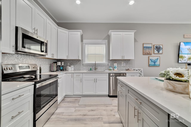 kitchen with tasteful backsplash, appliances with stainless steel finishes, white cabinets, and a sink