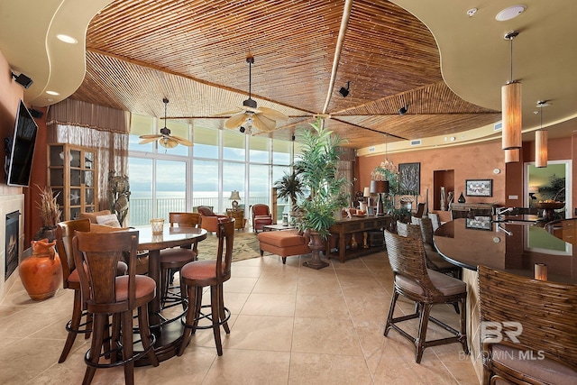 dining area featuring wooden ceiling, a water view, ceiling fan, light tile patterned flooring, and a wall of windows