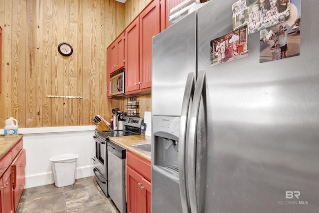 kitchen featuring wooden walls, appliances with stainless steel finishes, and light countertops