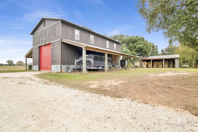 view of front of property featuring an outbuilding, driveway, an outdoor structure, a carport, and a garage