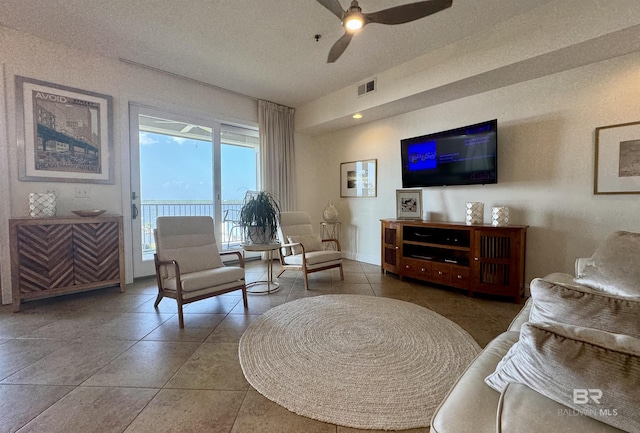 sitting room with a textured ceiling, a ceiling fan, visible vents, vaulted ceiling, and tile patterned floors