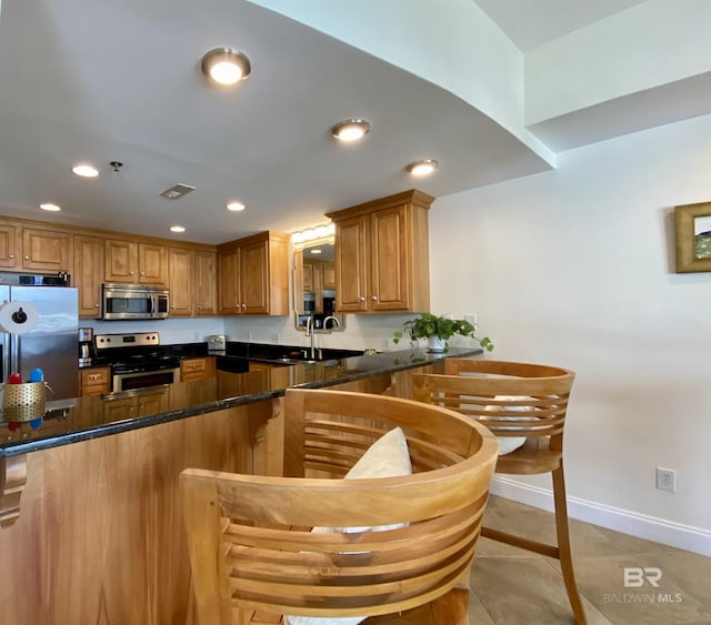 kitchen featuring visible vents, brown cabinets, stainless steel appliances, a sink, and recessed lighting