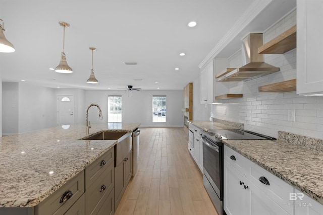 kitchen featuring appliances with stainless steel finishes, pendant lighting, white cabinetry, sink, and wall chimney exhaust hood