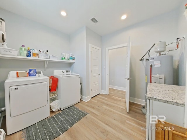 laundry room with washer and clothes dryer, light hardwood / wood-style floors, and water heater