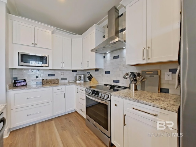 kitchen with extractor fan, white cabinetry, tasteful backsplash, light wood-type flooring, and stainless steel appliances