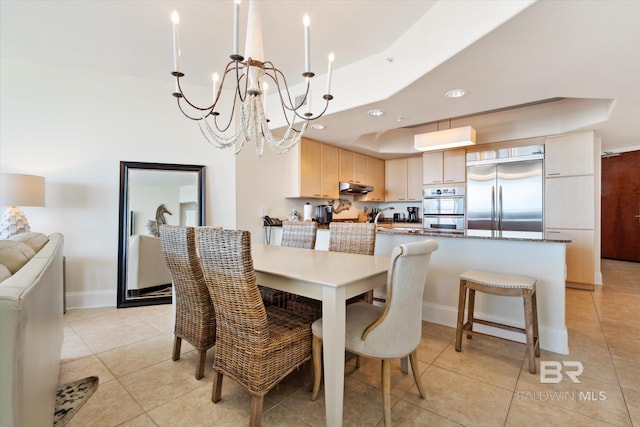 dining area featuring a chandelier, a tray ceiling, and light tile patterned floors