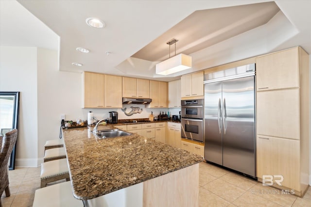 kitchen featuring kitchen peninsula, a breakfast bar, sink, pendant lighting, and stainless steel appliances