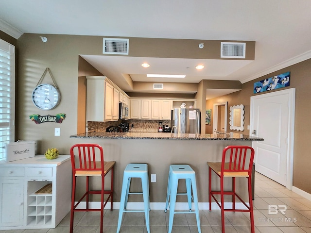 kitchen with a breakfast bar area, kitchen peninsula, white cabinets, and appliances with stainless steel finishes