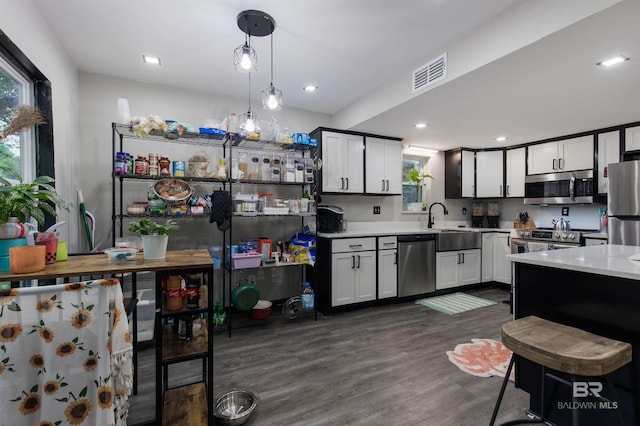 kitchen featuring pendant lighting, stainless steel appliances, white cabinets, and dark wood-type flooring