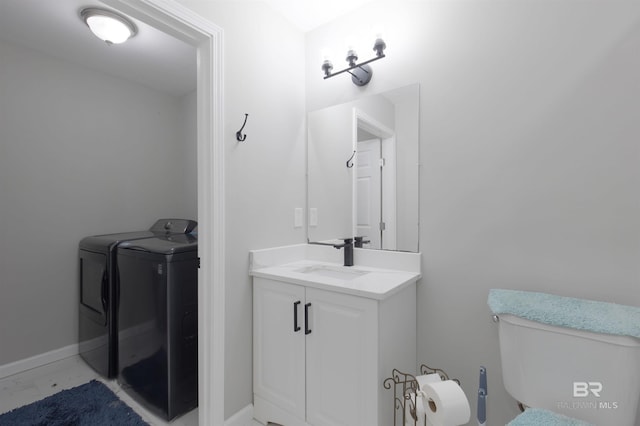 half bath with baseboards, vanity, washer and dryer, and toilet
