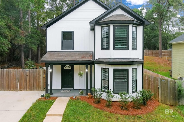 view of front of home featuring a front lawn, board and batten siding, a shingled roof, fence, and a porch