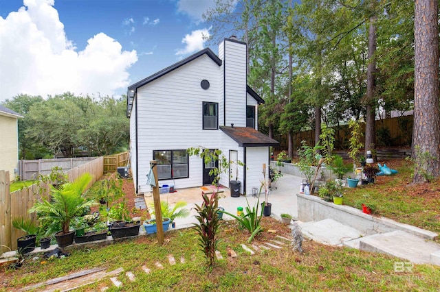 rear view of property featuring a chimney, a patio area, and a fenced backyard
