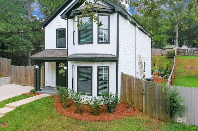 view of front of property with a gate, fence private yard, board and batten siding, and a front yard