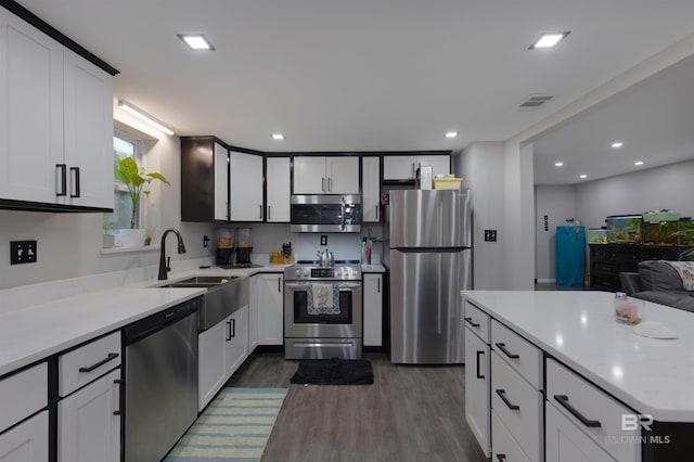 kitchen with a sink, light countertops, dark wood finished floors, appliances with stainless steel finishes, and visible vents