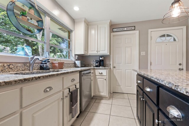 kitchen with white cabinetry, sink, dishwasher, light stone counters, and light tile patterned floors