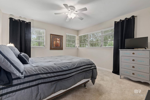 bedroom with light carpet, multiple windows, and ceiling fan