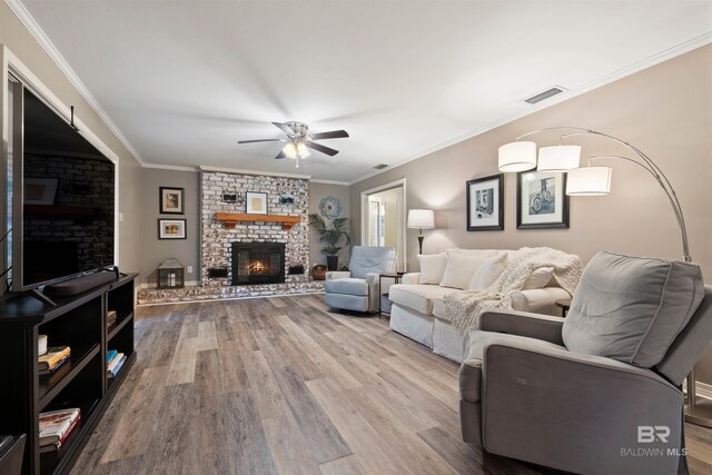 living room with hardwood / wood-style flooring, a fireplace, brick wall, ceiling fan, and ornamental molding