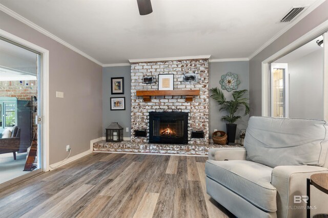 living room with ornamental molding, a brick fireplace, hardwood / wood-style flooring, and ceiling fan