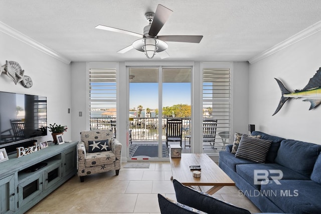 living room with a textured ceiling, ceiling fan, tile floors, and ornamental molding