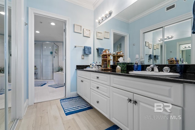 bathroom featuring vanity with extensive cabinet space, an enclosed shower, crown molding, tile floors, and double sink