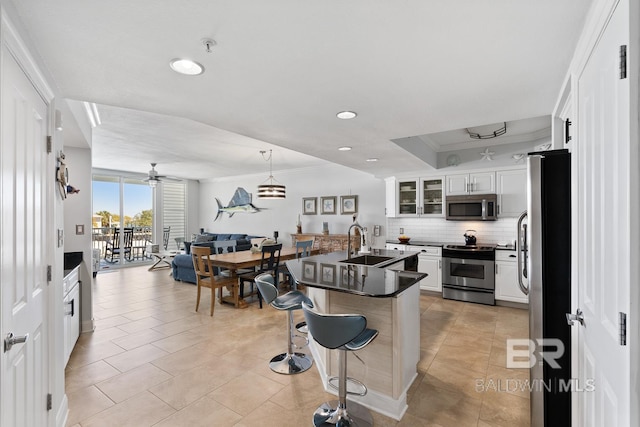 kitchen featuring white cabinetry, appliances with stainless steel finishes, tasteful backsplash, a kitchen island with sink, and a kitchen breakfast bar