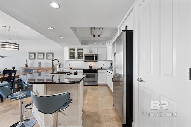 kitchen with a kitchen island, a kitchen bar, white cabinetry, stainless steel appliances, and pendant lighting