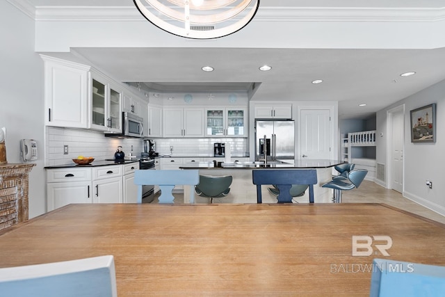 kitchen featuring a center island, stainless steel appliances, white cabinets, and backsplash