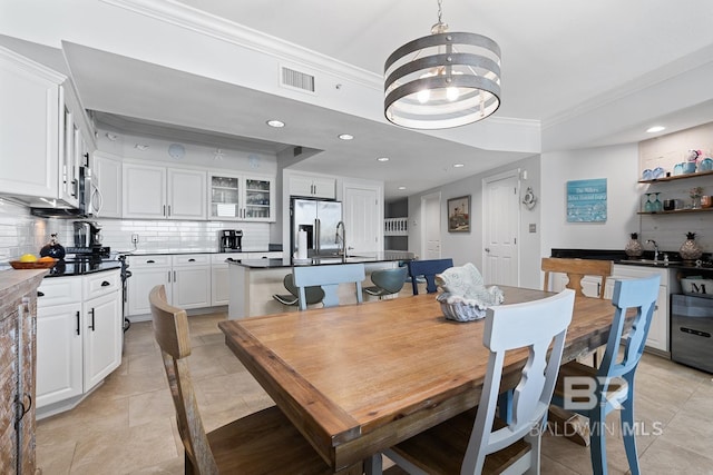 tiled dining room featuring sink, crown molding, and a notable chandelier