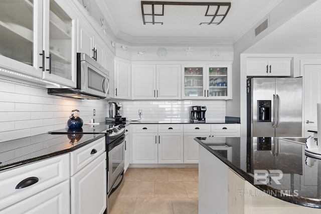 kitchen with white cabinets, ornamental molding, stainless steel appliances, tasteful backsplash, and dark stone countertops