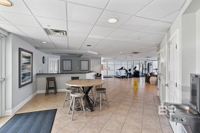 tiled dining area with a drop ceiling