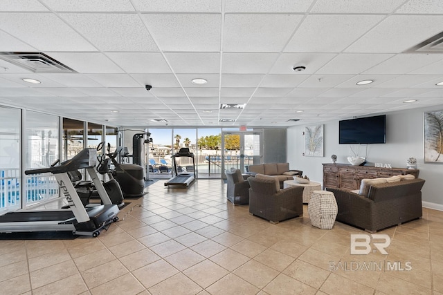 exercise room with a paneled ceiling, light tile floors, and a wall of windows