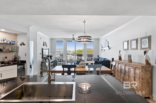 kitchen featuring white cabinets, sink, ceiling fan with notable chandelier, hanging light fixtures, and ornamental molding