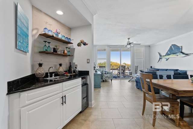 interior space featuring white cabinets, light tile flooring, crown molding, sink, and ceiling fan