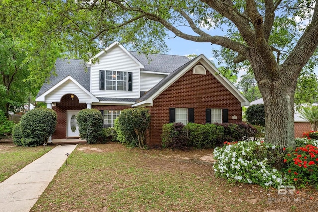 traditional-style home featuring brick siding, roof with shingles, and a front lawn