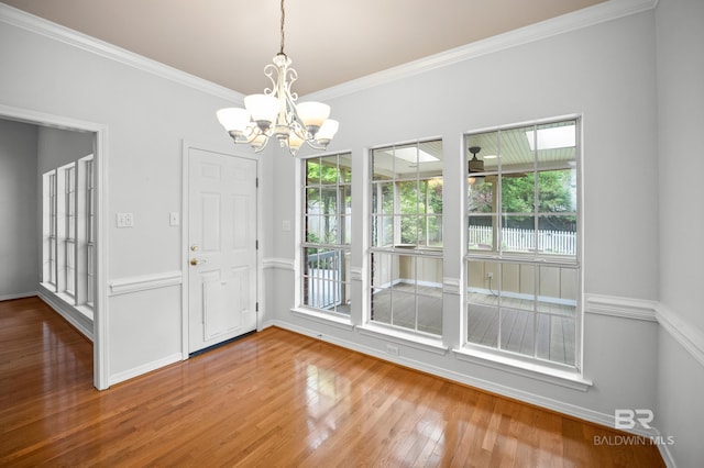 interior space featuring baseboards, ornamental molding, wood finished floors, and a chandelier