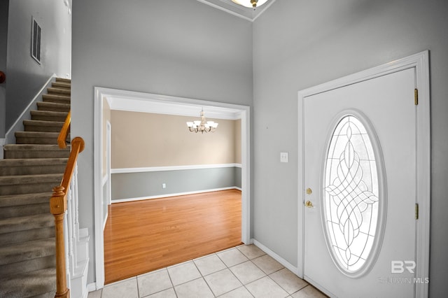 entryway featuring visible vents, baseboards, a notable chandelier, stairs, and light tile patterned flooring