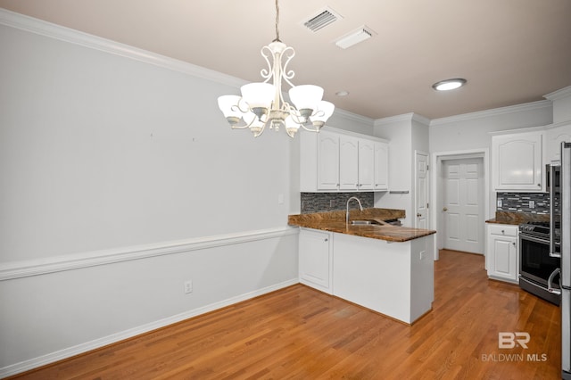 kitchen with a sink, white cabinetry, a notable chandelier, and tasteful backsplash