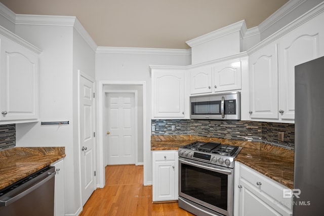 kitchen featuring ornamental molding, appliances with stainless steel finishes, white cabinets, and tasteful backsplash