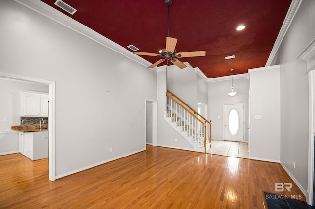 foyer featuring visible vents, ornamental molding, stairs, wood finished floors, and a ceiling fan