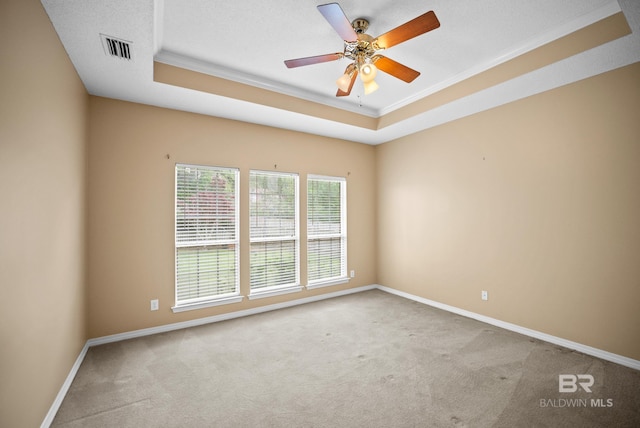 carpeted empty room with a tray ceiling, ceiling fan, ornamental molding, and baseboards