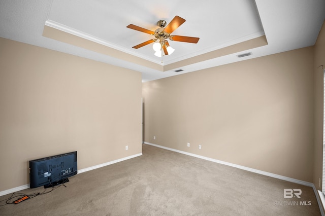carpeted spare room featuring crown molding, ceiling fan, visible vents, and a raised ceiling
